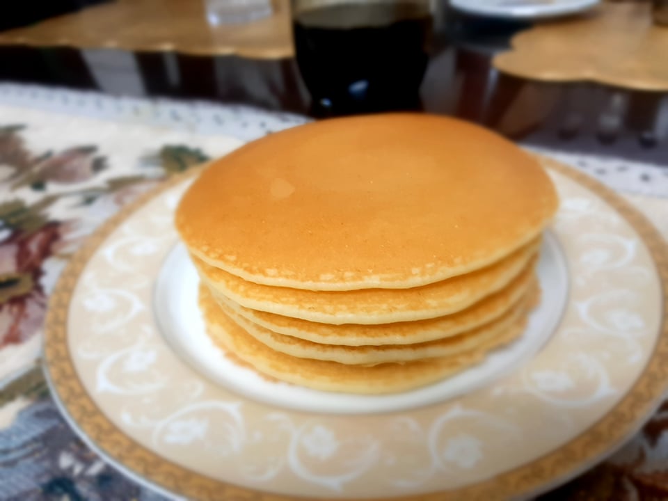 tack of golden brown vegan pancakes with a side of fresh berries and a drizzle of maple syrup on a white plate. The pancakes are light and fluffy, with a slightly crispy exterior and a soft, fluffy interior. This vegan breakfast is both satisfying and delicious, and can be easily customized with different toppings to suit your taste preferences.