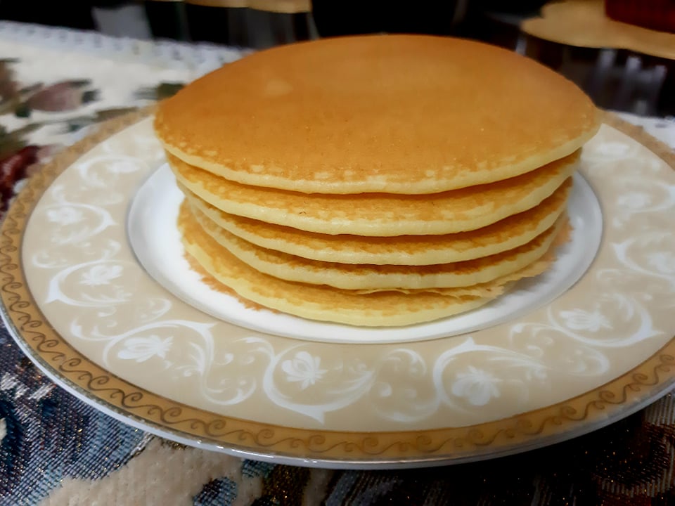 Stack of golden brown vegan pancakes with a side of fresh berries and a drizzle of maple syrup on a white plate. The pancakes are light and fluffy, with a slightly crispy exterior and a soft, fluffy interior. This vegan breakfast is both satisfying and delicious, and can be easily customized with different toppings to suit your taste preferences.